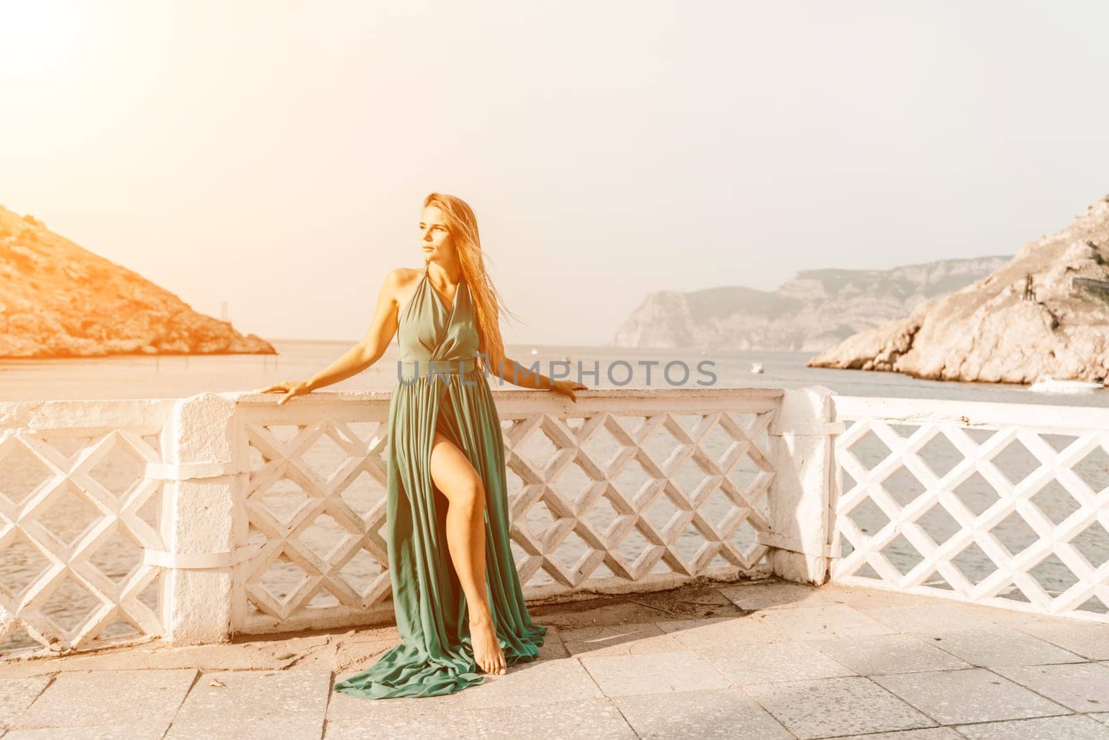 Woman sea trevel green dress. Side view a happy woman with long hair in a long mint dress posing on a beach with calm sea bokeh lights on sunny day. Girl on the nature on blue sky background. by Matiunina