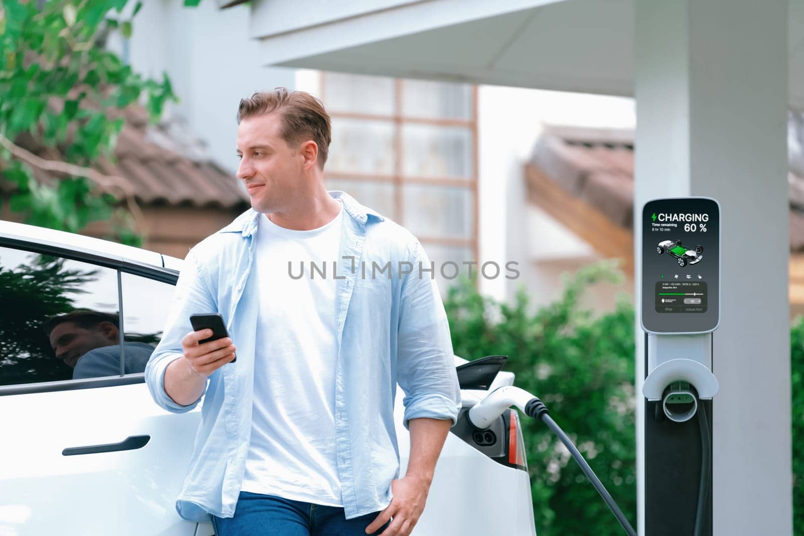 Modern eco man recharge EV car at home with phone. Synchronos by biancoblue