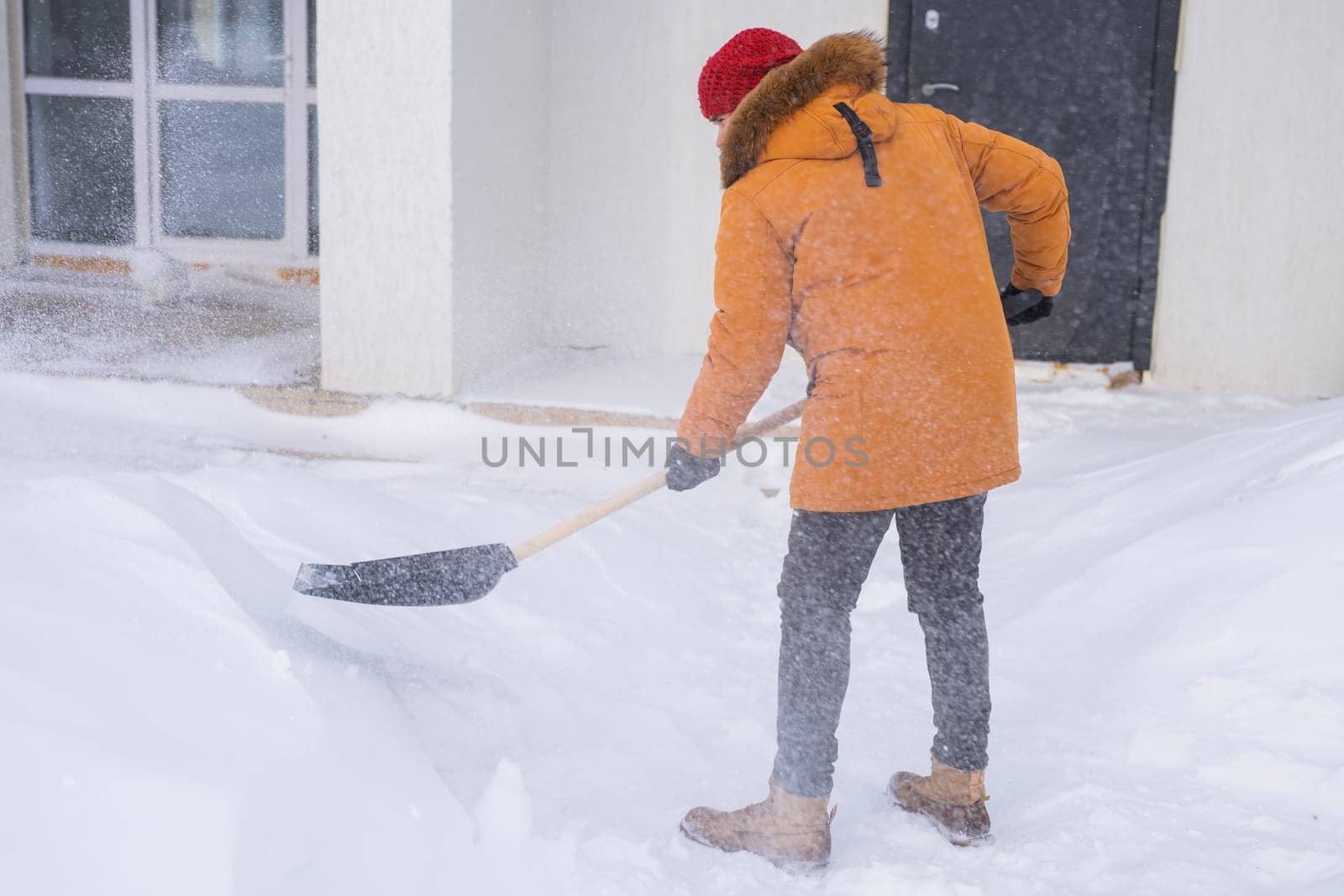 Man is clearing the snow near house and on staircases hovelling at the winter season. Winter storm and season specific.