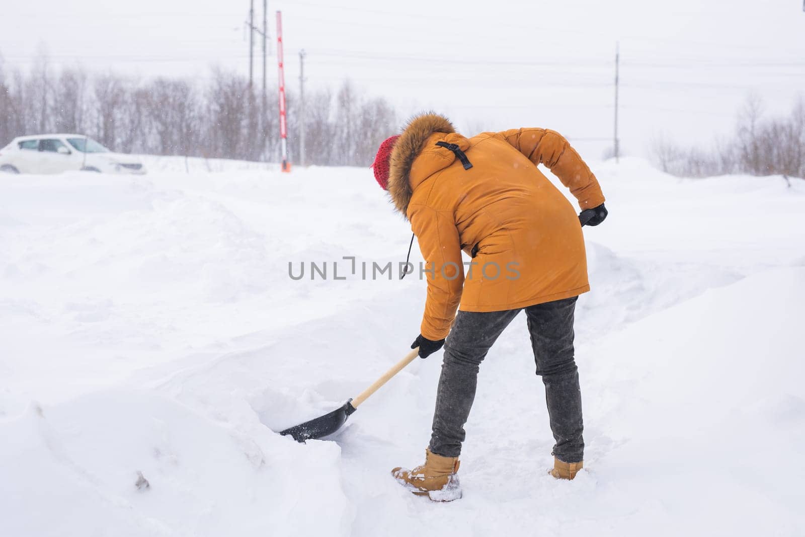 Young man clearing snow in his backyard village house with shovel. Remove snow from the sidewalk