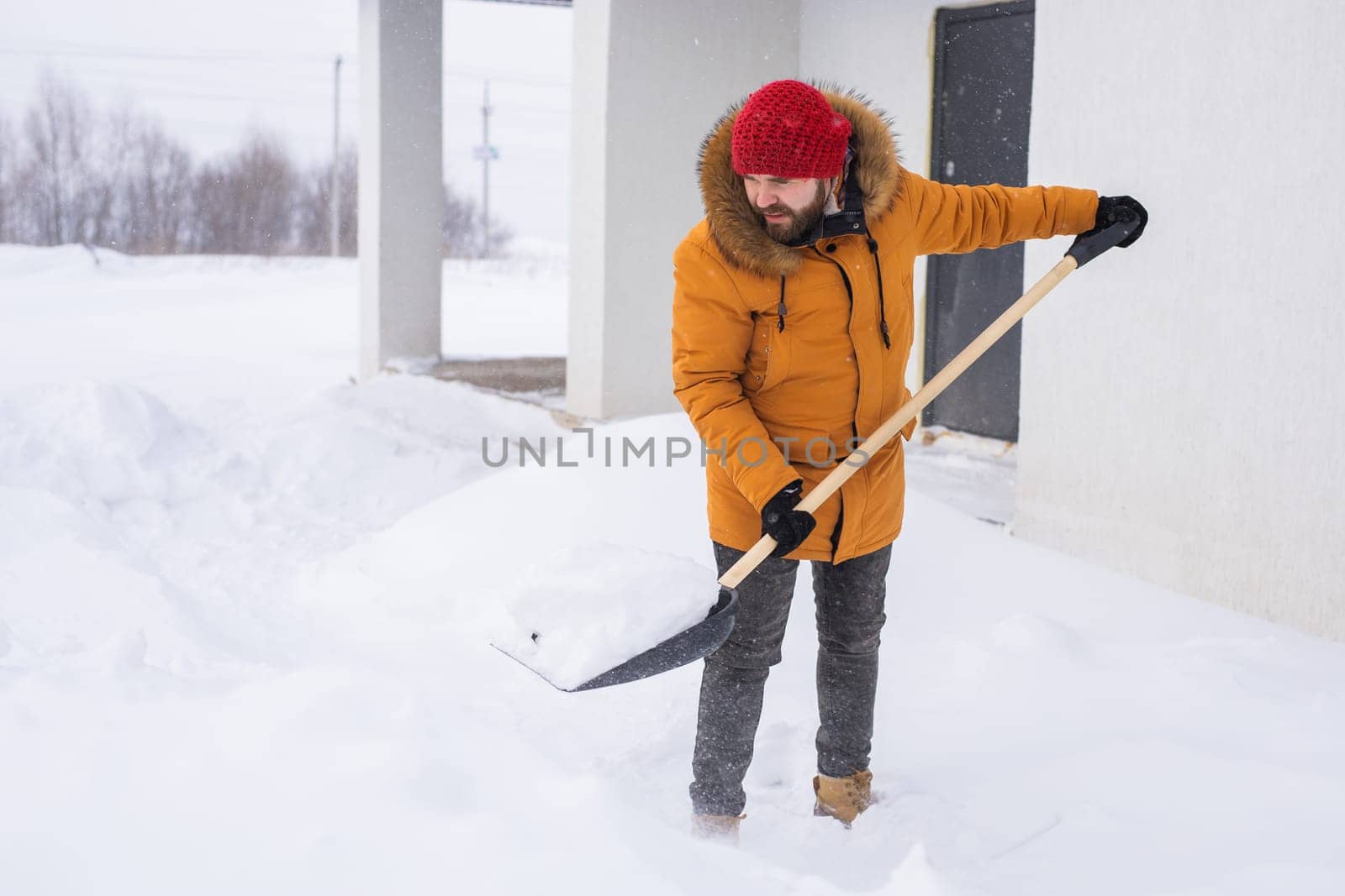 Man is clearing the snow near house and on staircases hovelling at the winter season. Winter storm and season specific.