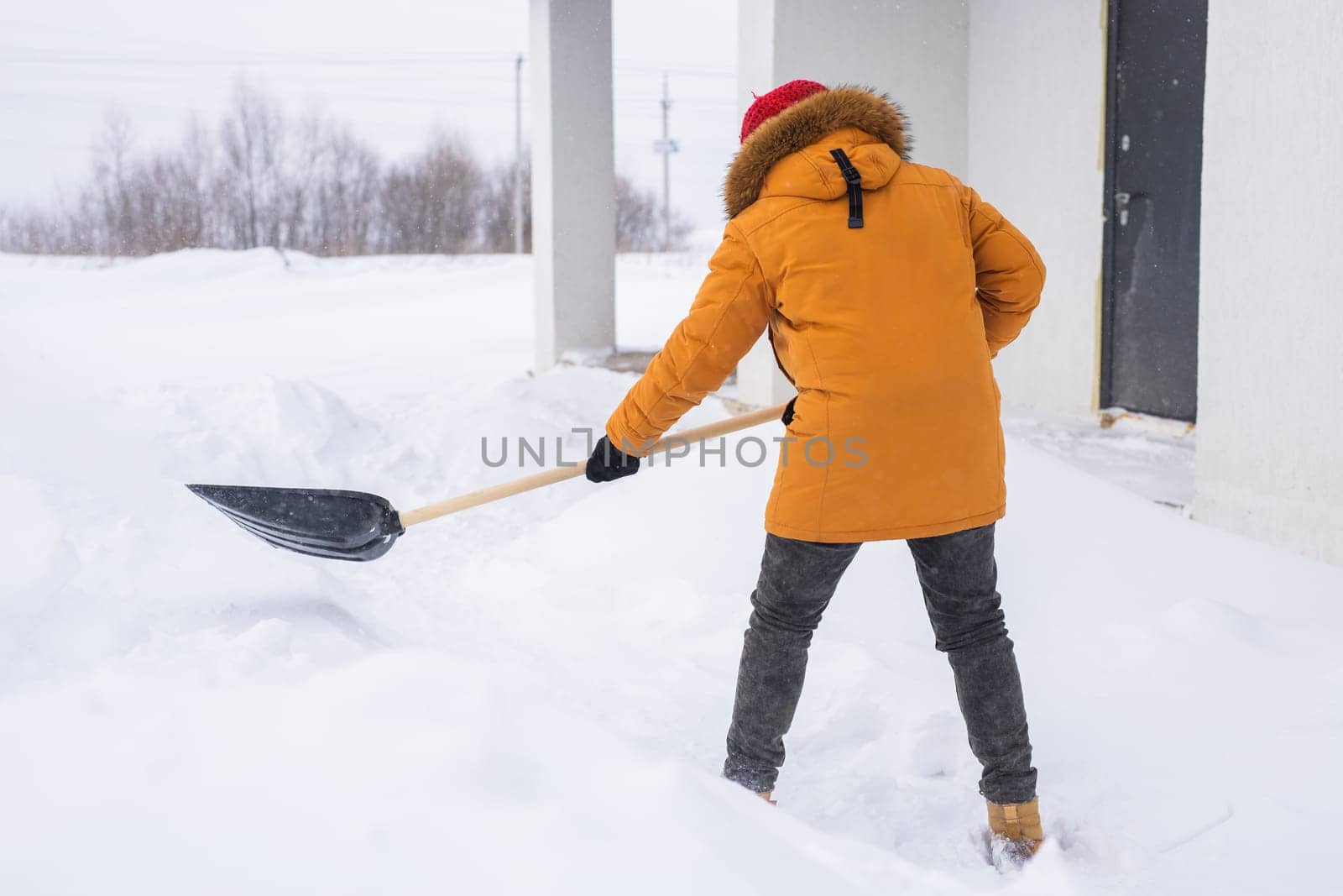 Man is clearing the snow near house and on staircases hovelling at the winter season. Winter storm and season specific.