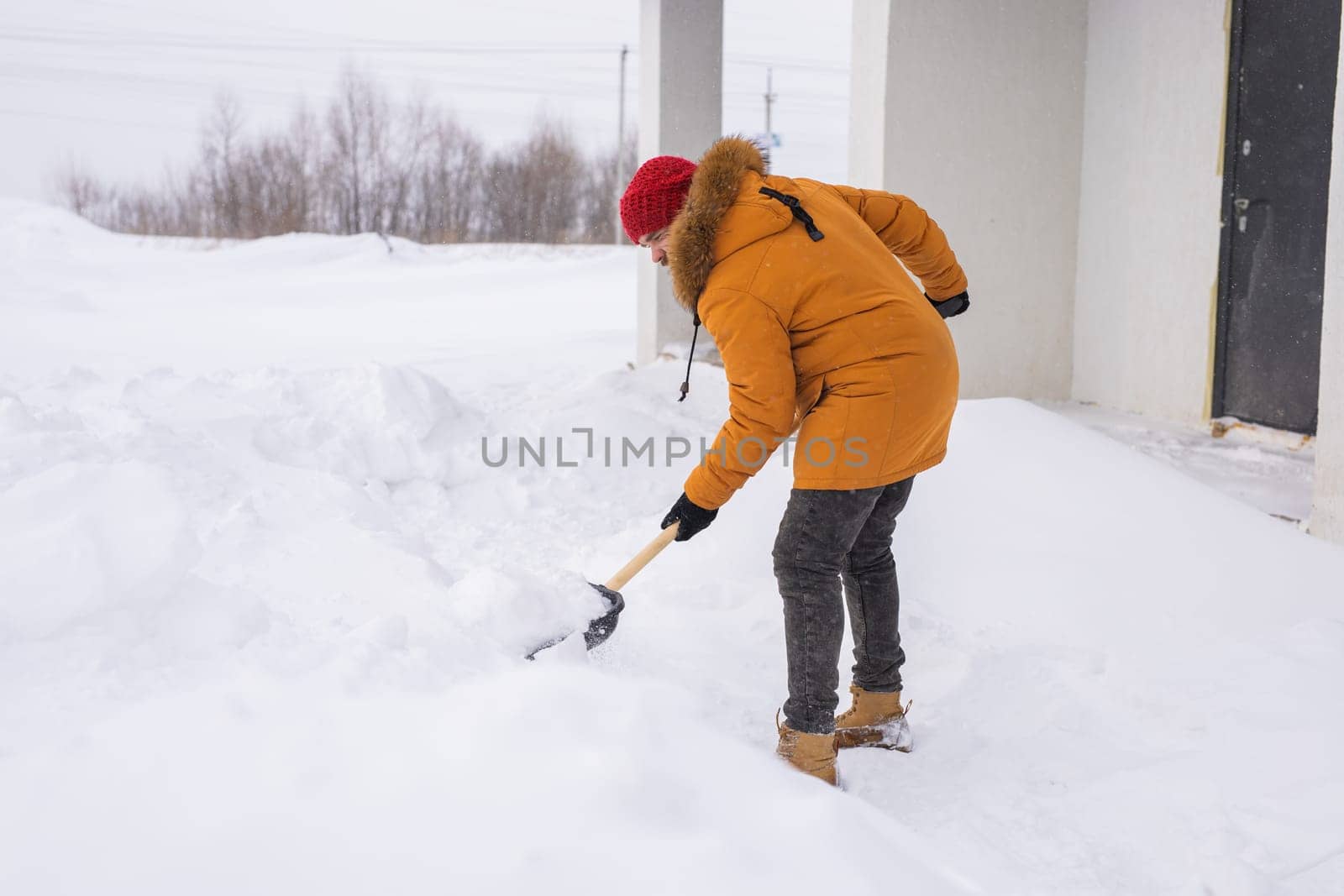 Man removing snow and ice from the sidewalk in front of house. Winter season by Satura86