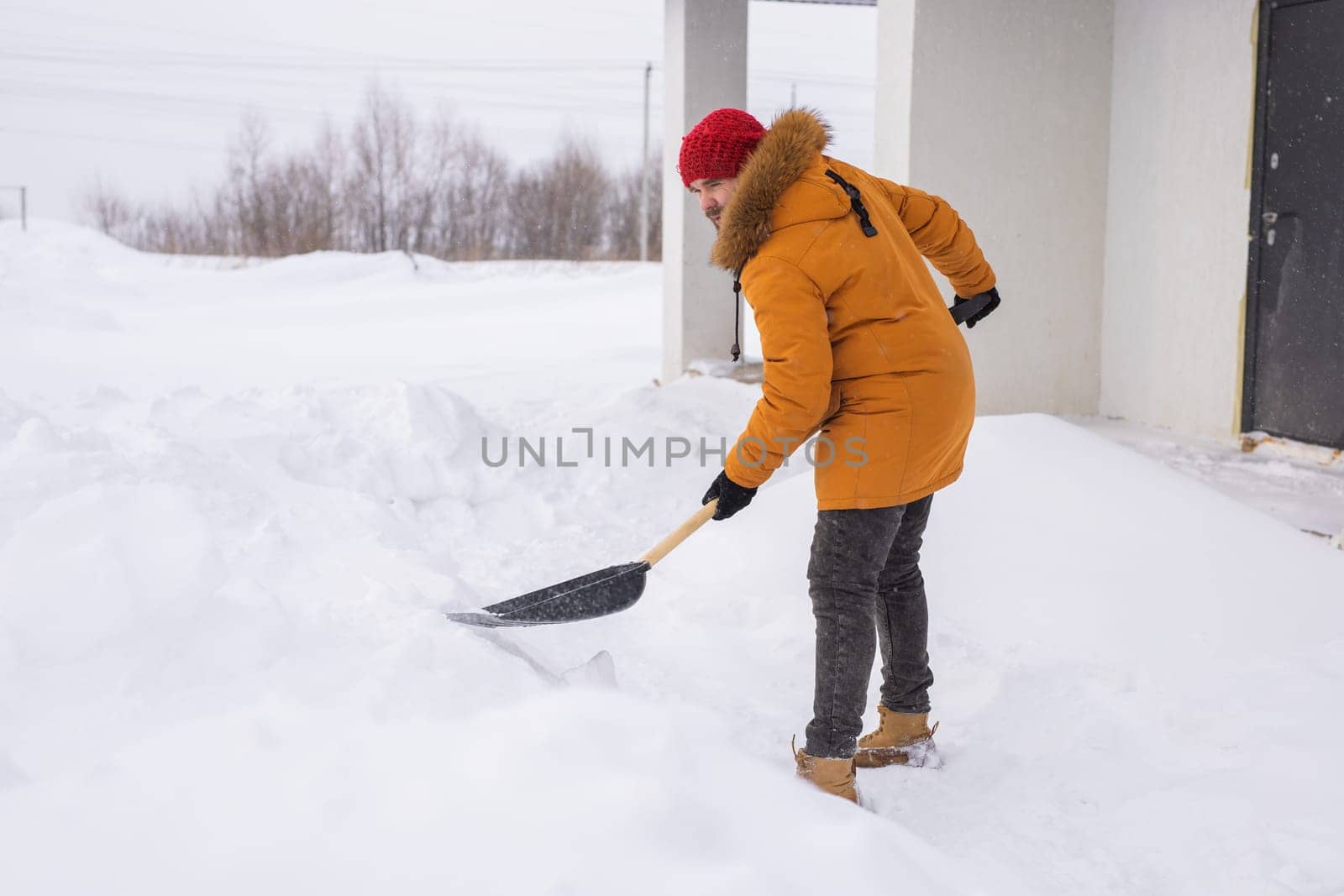 Man is clearing the snow near house and on staircases hovelling at the winter season. Winter storm and season specific by Satura86