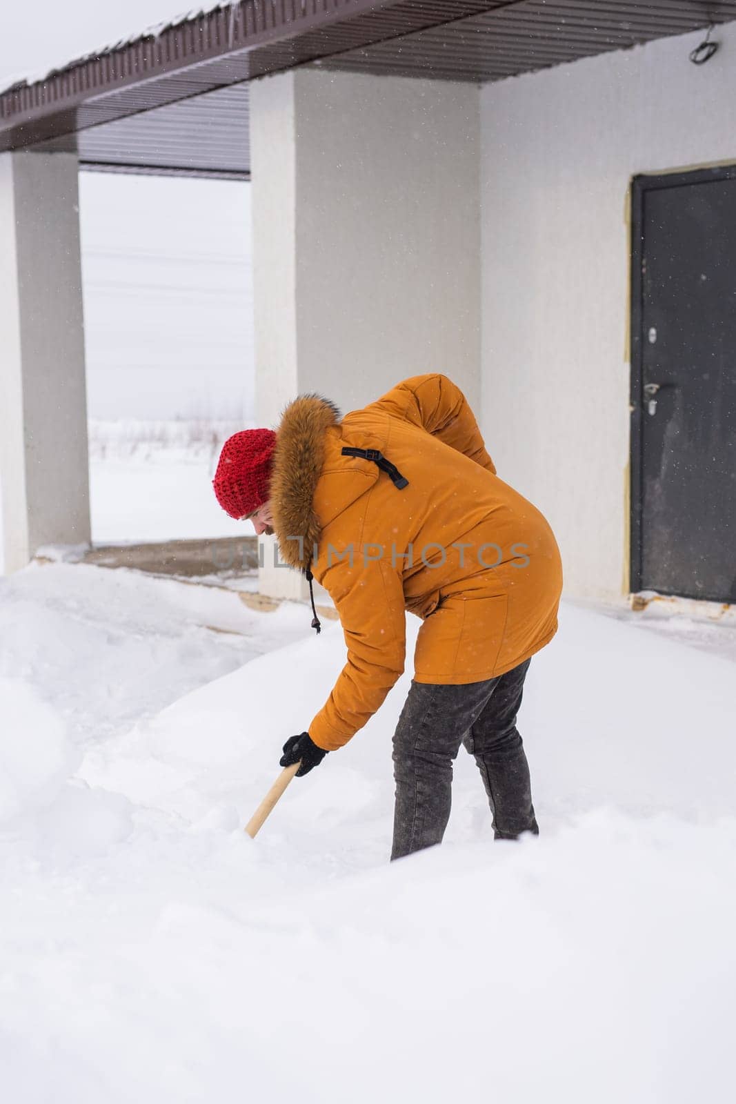Man is clearing the snow near house and on staircases hovelling at the winter season. Winter storm and season specific by Satura86