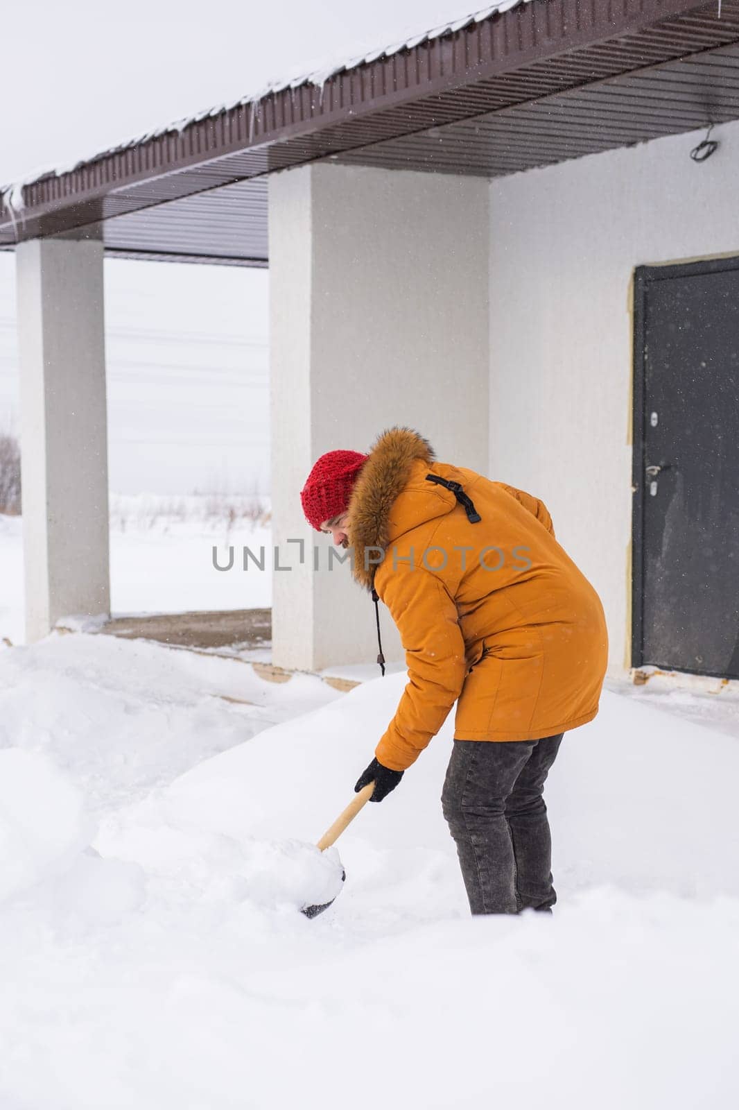 Man cleaning snow from sidewalk and using snow shovel. Winter season by Satura86