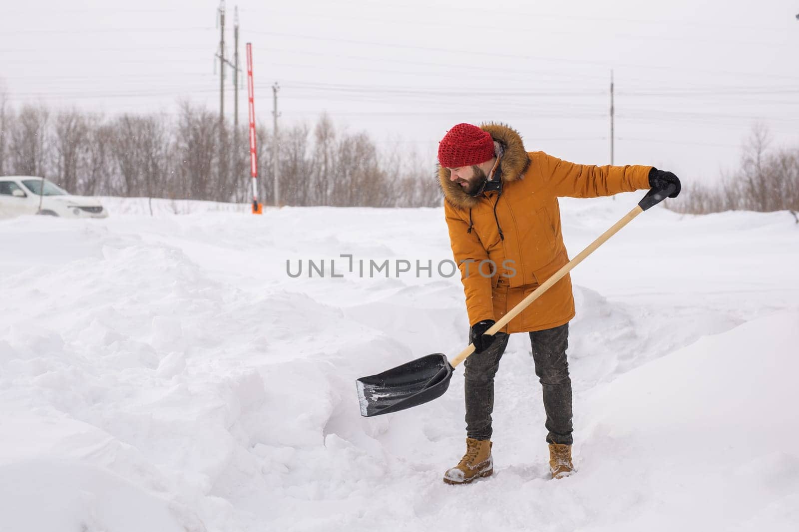 Young man clearing snow in his backyard village house with shovel. Remove snow from the sidewalk