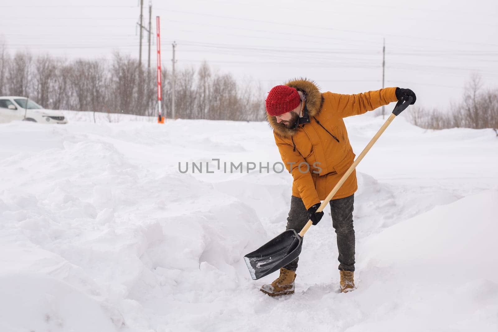 A man cleans and clears the snow in front of the house on frosty day. Cleaning the street from snow on a winter day. Snowfall and severe snowstorm in winter. by Satura86