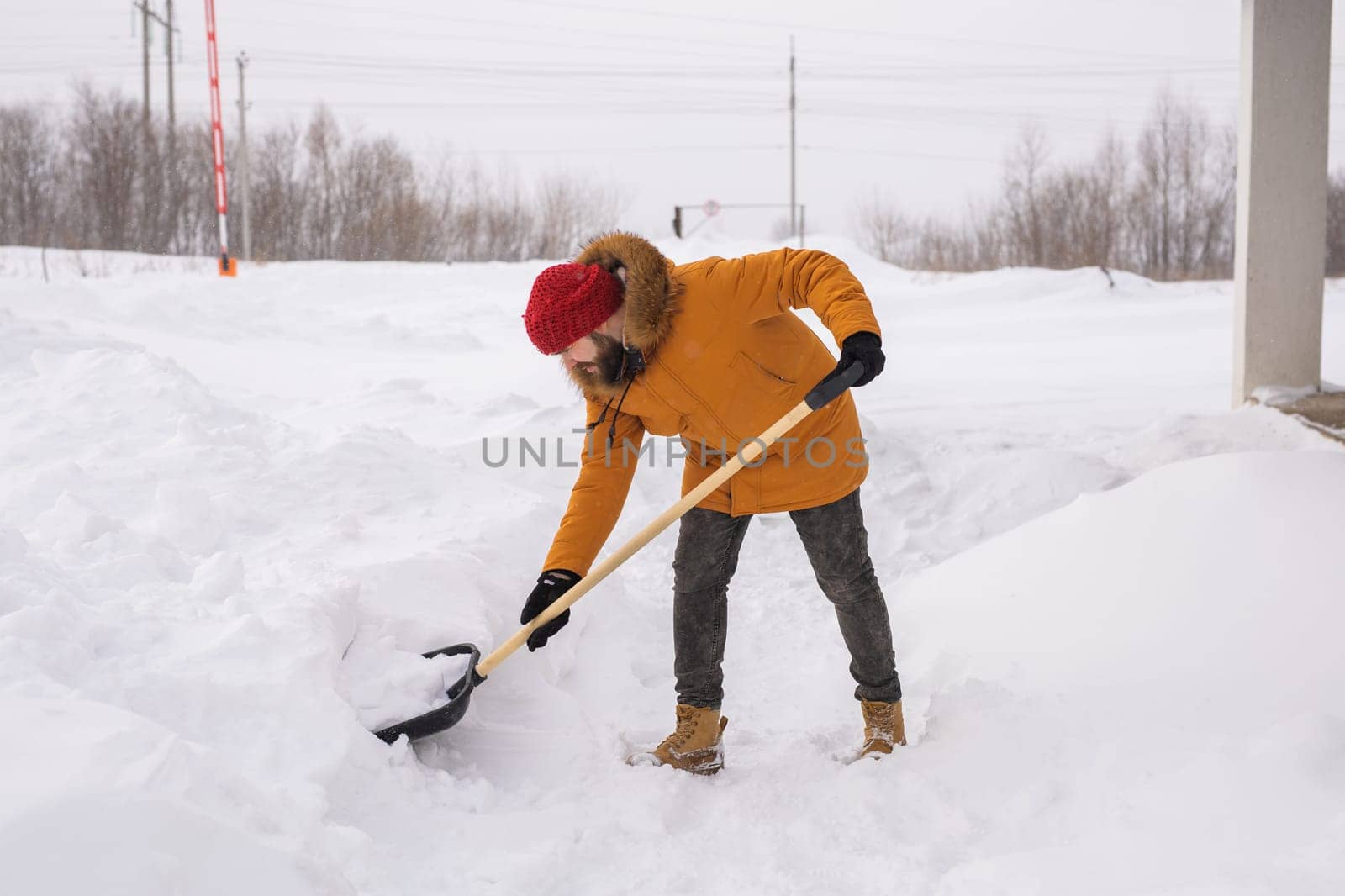 Man removing snow and ice from the sidewalk in front of house. Winter season.