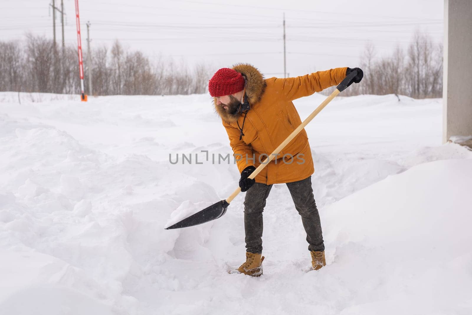 A man cleans and clears the snow in front of the house on frosty day. Cleaning the street from snow on a winter day. Snowfall and severe snowstorm in winter