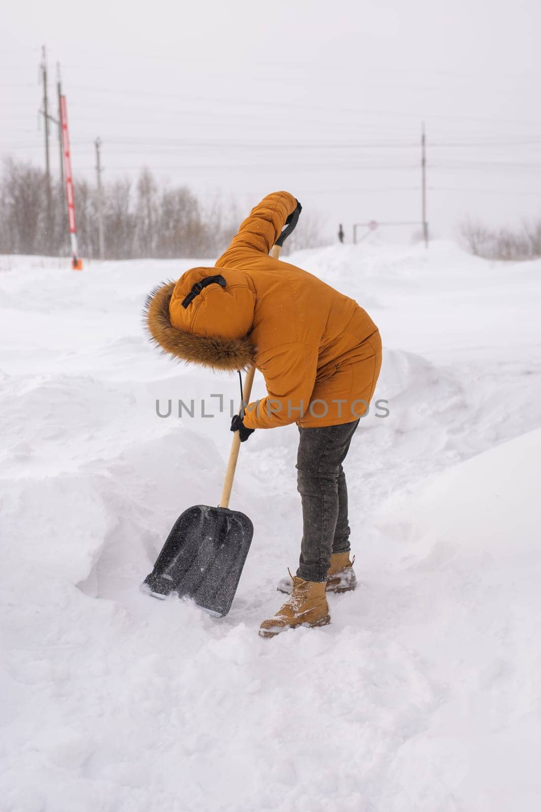 A man cleans and clears the snow in front of the house on frosty day. Cleaning the street from snow on a winter day. Snowfall and severe snowstorm in winter