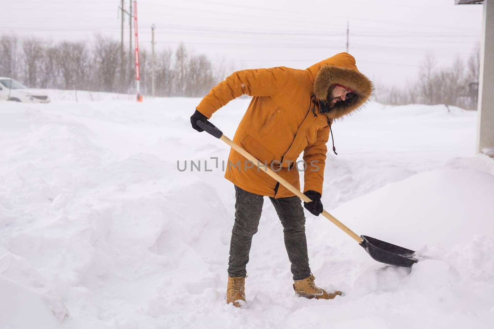 Man cleaning snow from sidewalk and using snow shovel. Winter season.