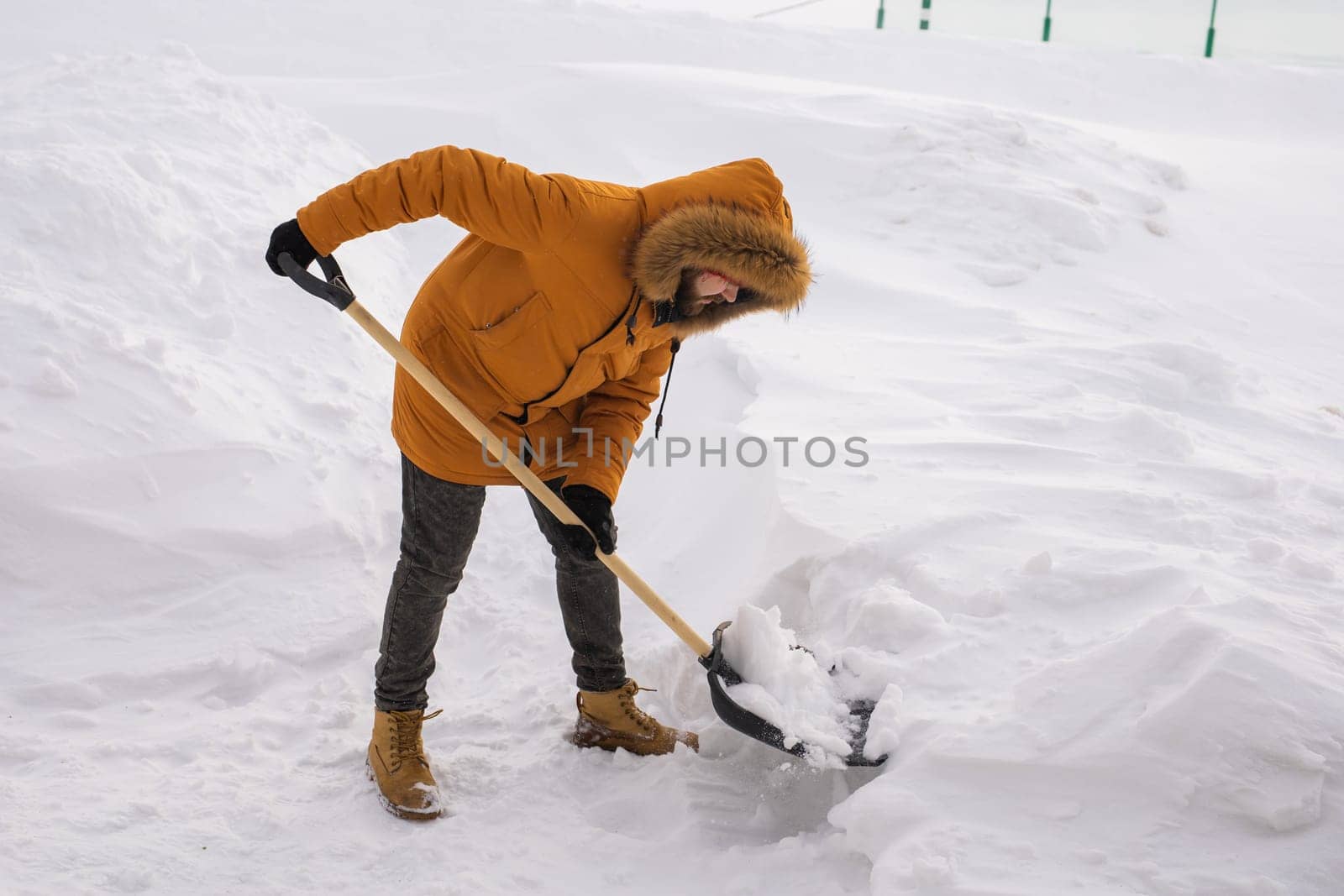 Man removing snow and ice from the sidewalk in front of house. Winter season.