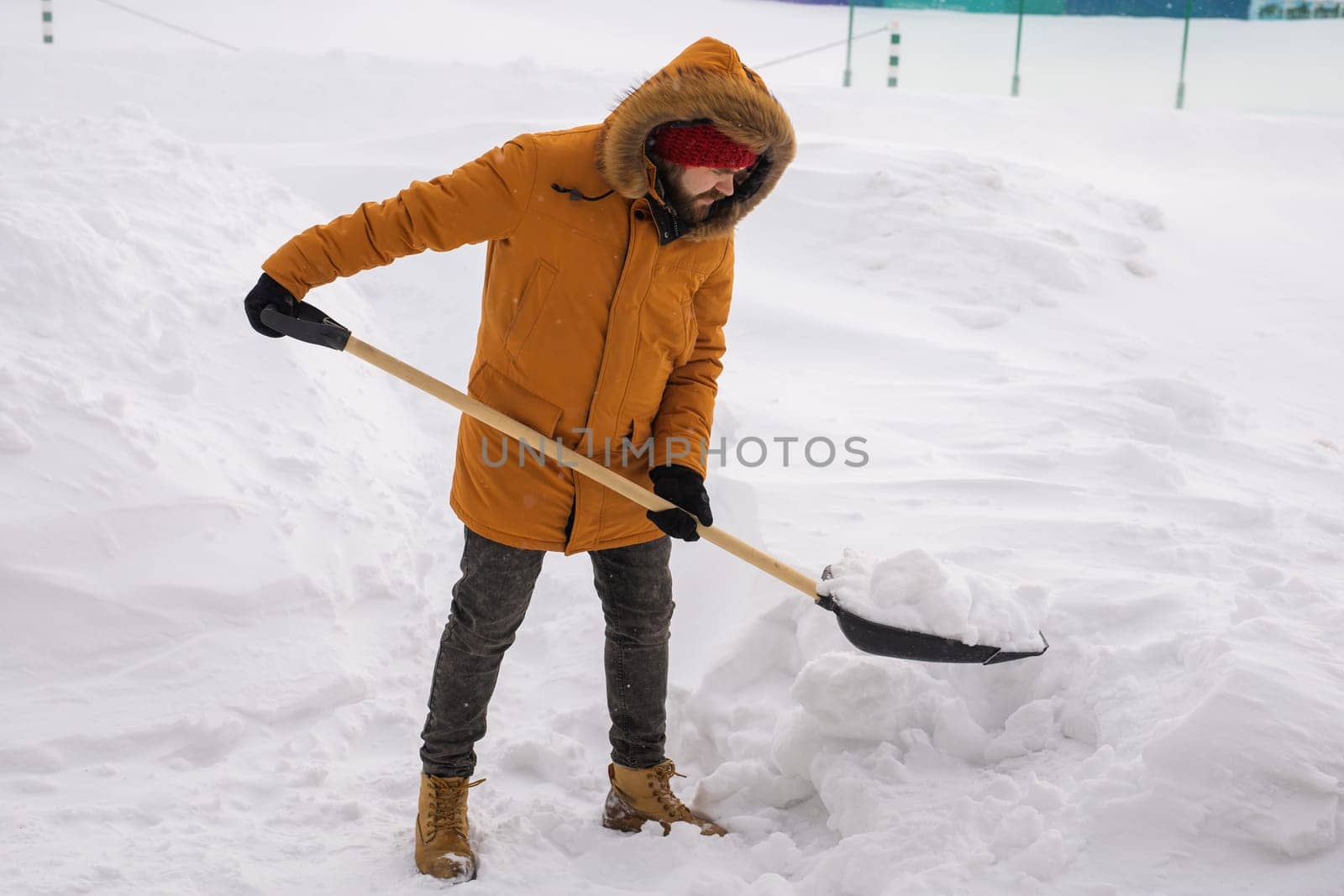 A man cleans and clears the snow in front of the house on frosty day. Cleaning the street from snow on a winter day. Snowfall and severe snowstorm in winter. by Satura86