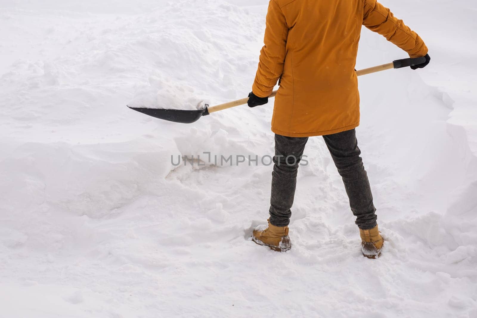 Close up man cleaning snow from sidewalk and using snow shovel. Winter season by Satura86