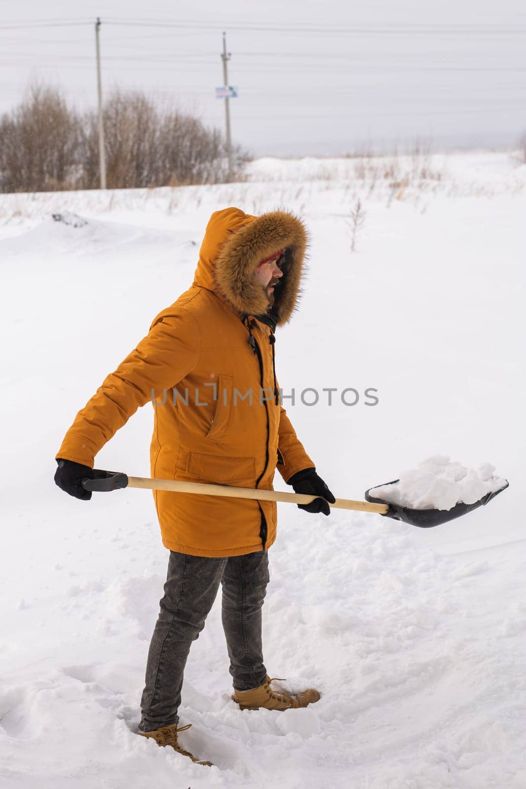 Man cleaning snow from sidewalk and using snow shovel. Winter season.