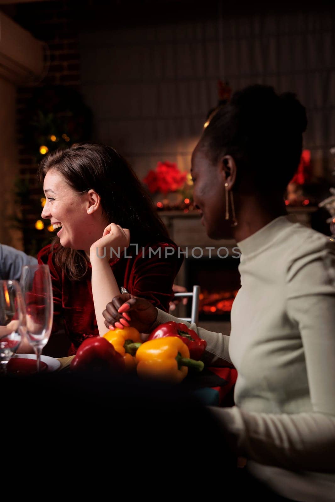 Cheerful woman having fun on xmas holiday, gathering with group of friends at dinner table and enjoying good food. Joyful festive person having fun with people at home, drinking wine.