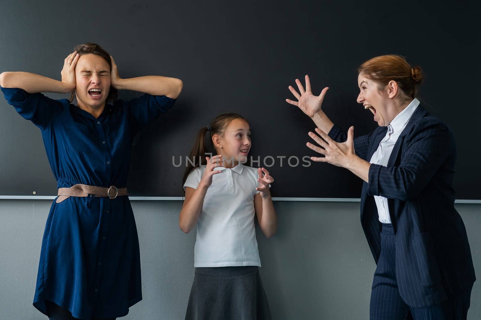 The female teacher screams at the schoolgirl and her mother standing at the blackboard. by mrwed54