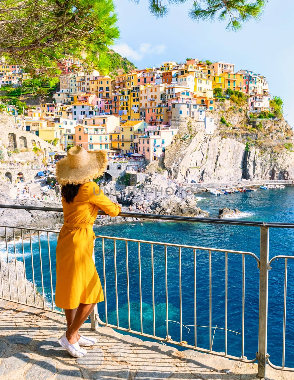 Asian women with a hat looking at Manarola in Cinque Terre Italy, Manarola Village Cinque Terre Coast Italy. Manarola is a beautiful colorful town of La Spezia, Liguria one of the five Cinque Terre