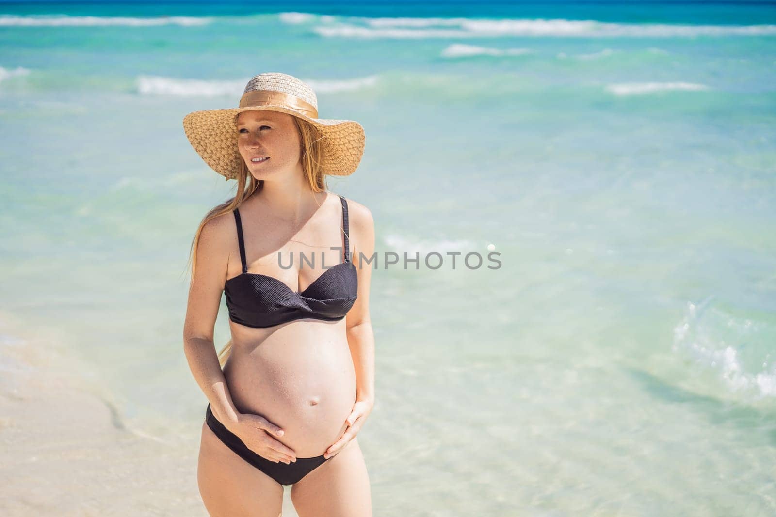 Radiant and expecting, a pregnant woman stands on a pristine snow-white tropical beach, celebrating the miracle of life against a backdrop of natural beauty by galitskaya