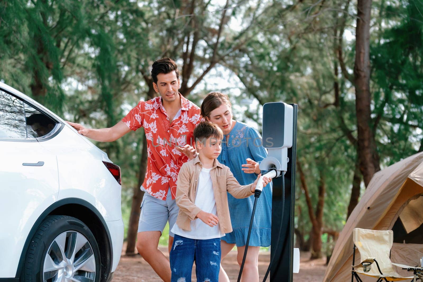 Lovely family recharge EV car with EV charging station in campsite. Perpetual by biancoblue