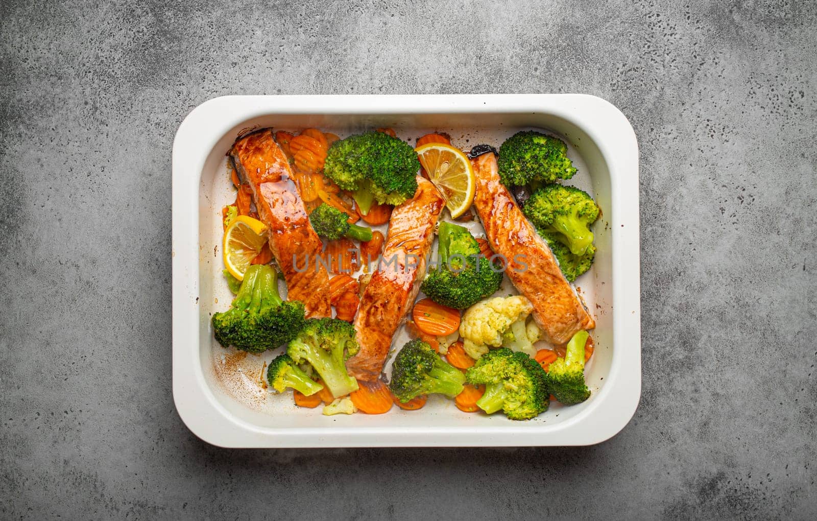Top view of healthy baked fish salmon steaks, broccoli, cauliflower, carrot in casserole dish. Cooking a delicious low carb dinner, healthy nutrition concept by its_al_dente