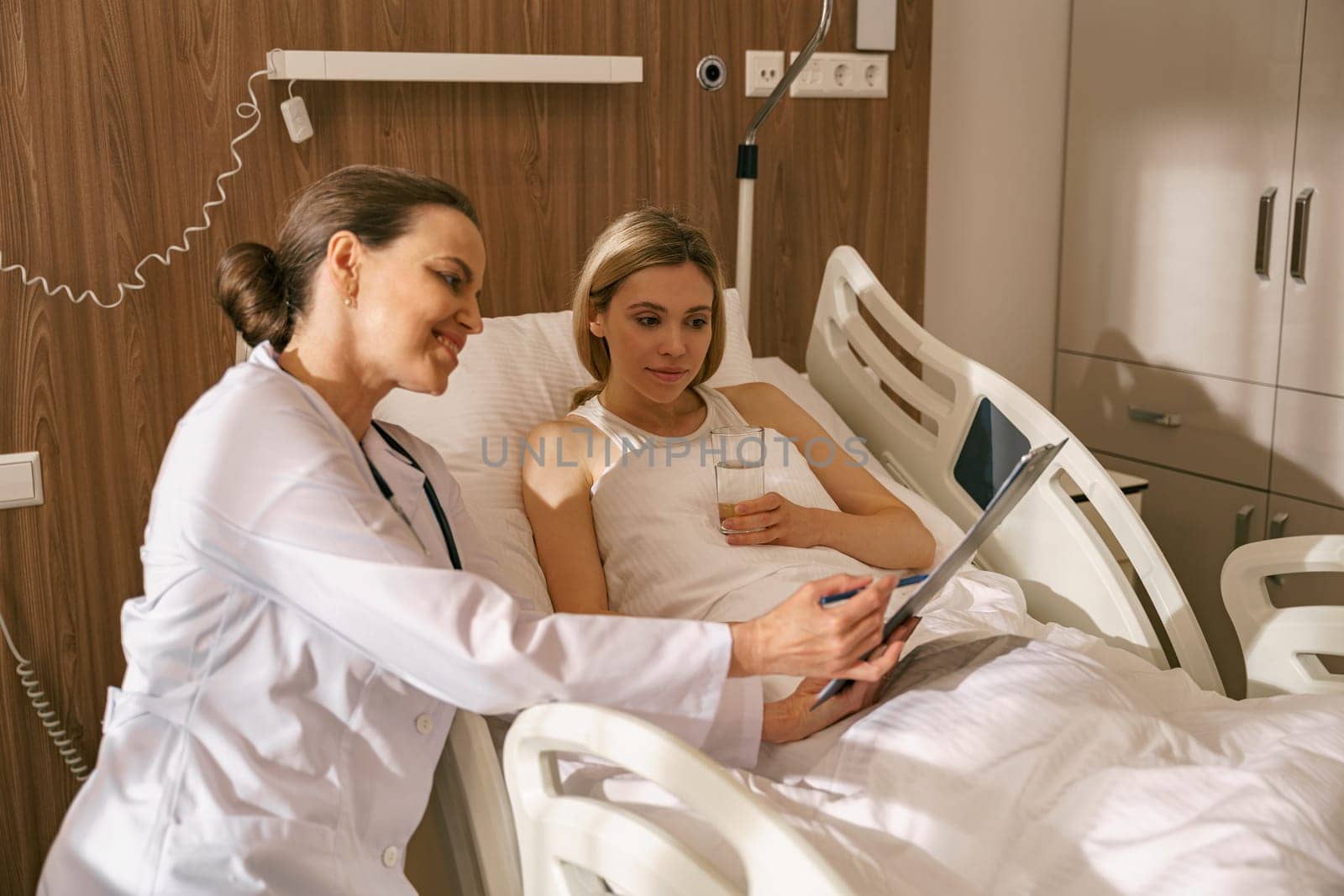Doctor visiting woman patient in hospital ward to check his health state . High quality photo