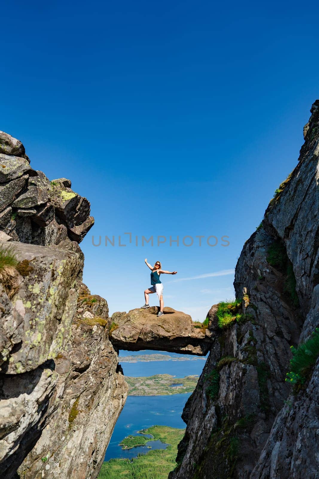 Brave traveler woman standing on hanging stone between rocks. Djevelporten in Norway Lofoten islands. Adventure, hiking, traveling, active lifestyle, vacation healthy lifestyle hiking in Scandinavia mountains. Kjeragbolten, Kjerag Bolt