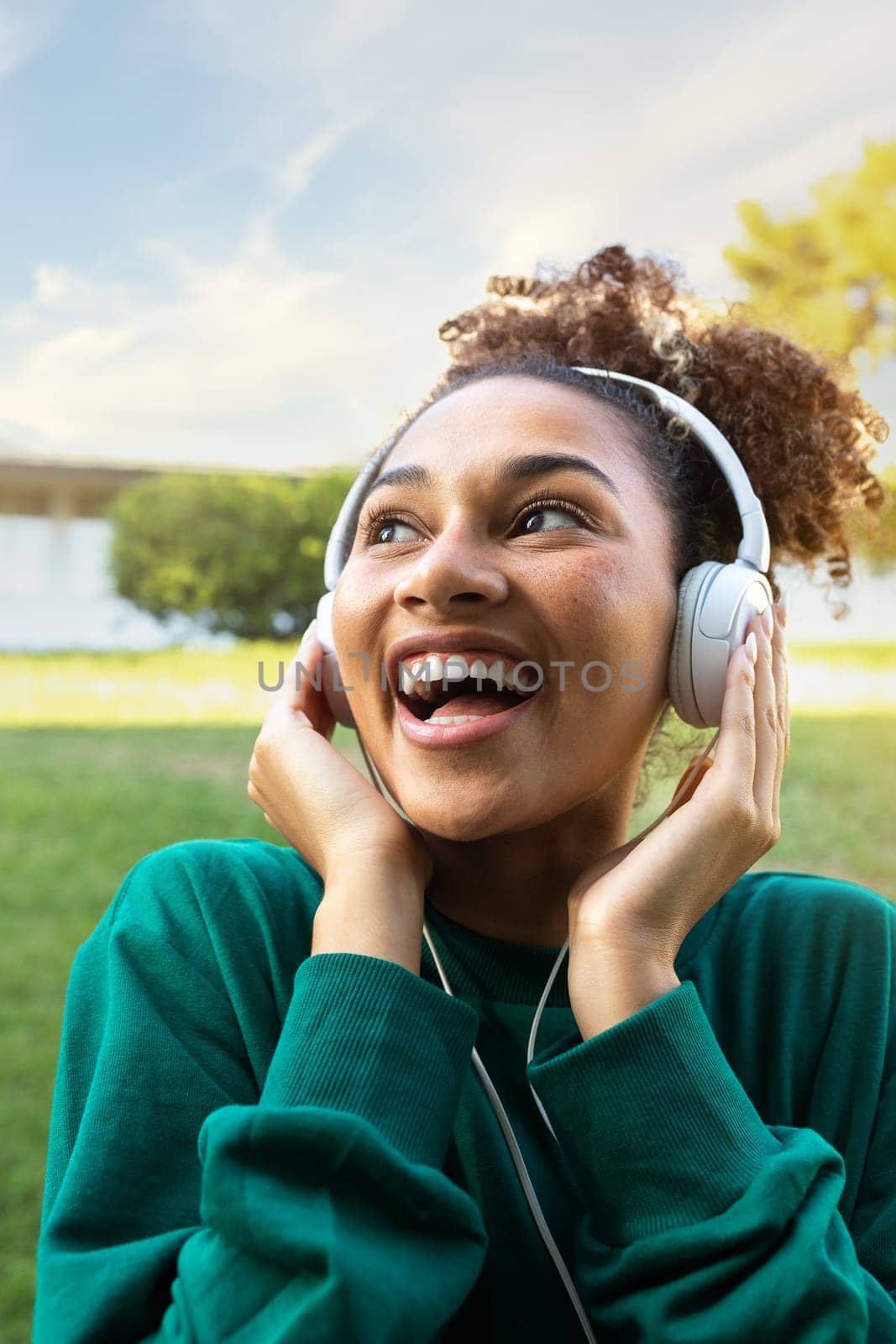 Vertical portrait of happy African American young woman listening to music using headphones. Lifestyle concept.