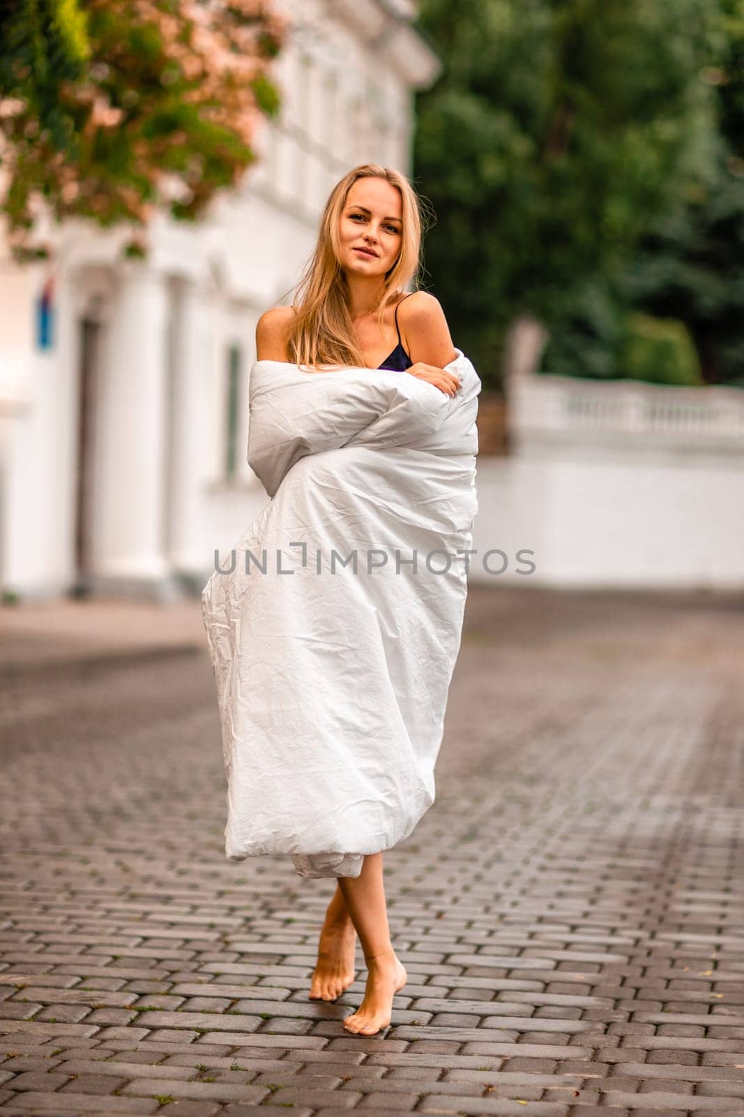 Woman city blanket. Morning in the big city. A blonde woman in a white blanket is enjoying in the city center. Photographed for social media.