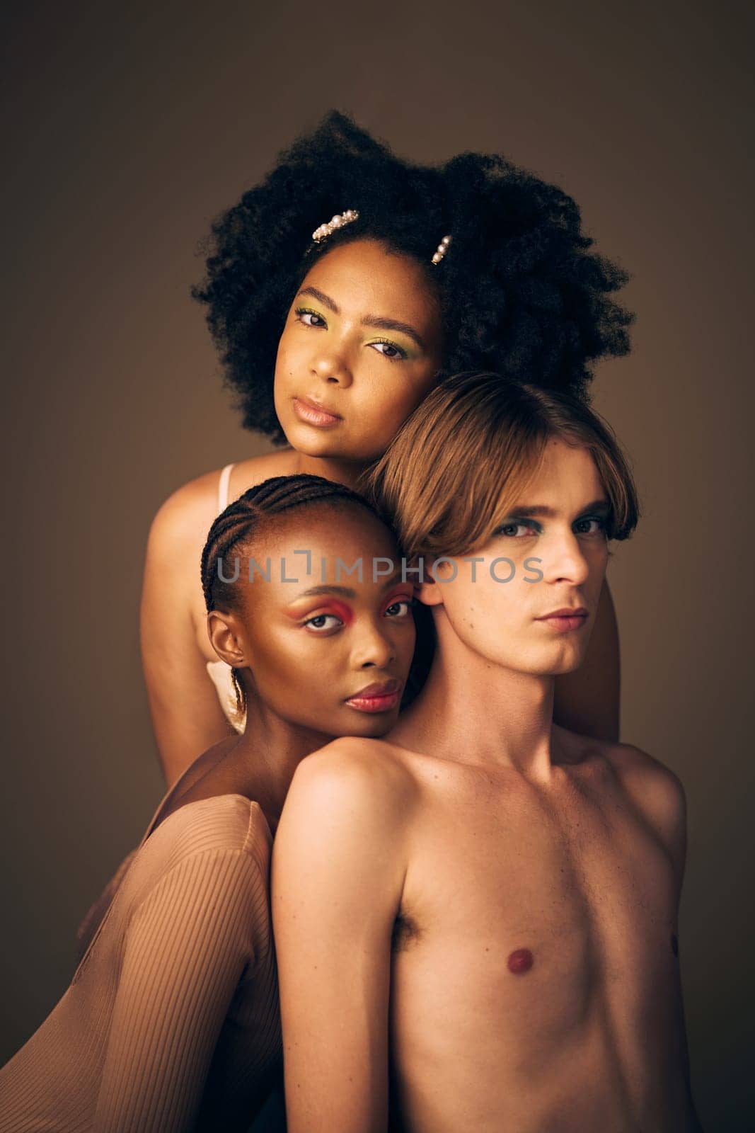 Makeup, glow and portrait of models in studio with creative, cosmetic and facial art for beauty. Queer, diversity and gen z man and women with face inclusion or skincare isolated by brown background. by YuriArcurs