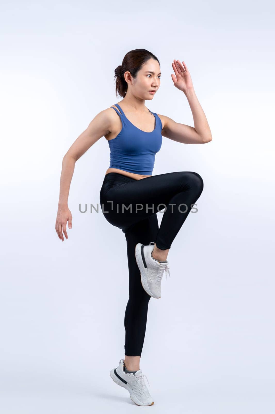 Side view young athletic asian woman on running posture in studio shot on isolated background. Pursuit of healthy fit body physique and cardio workout exercise lifestyle concept. Vigorous