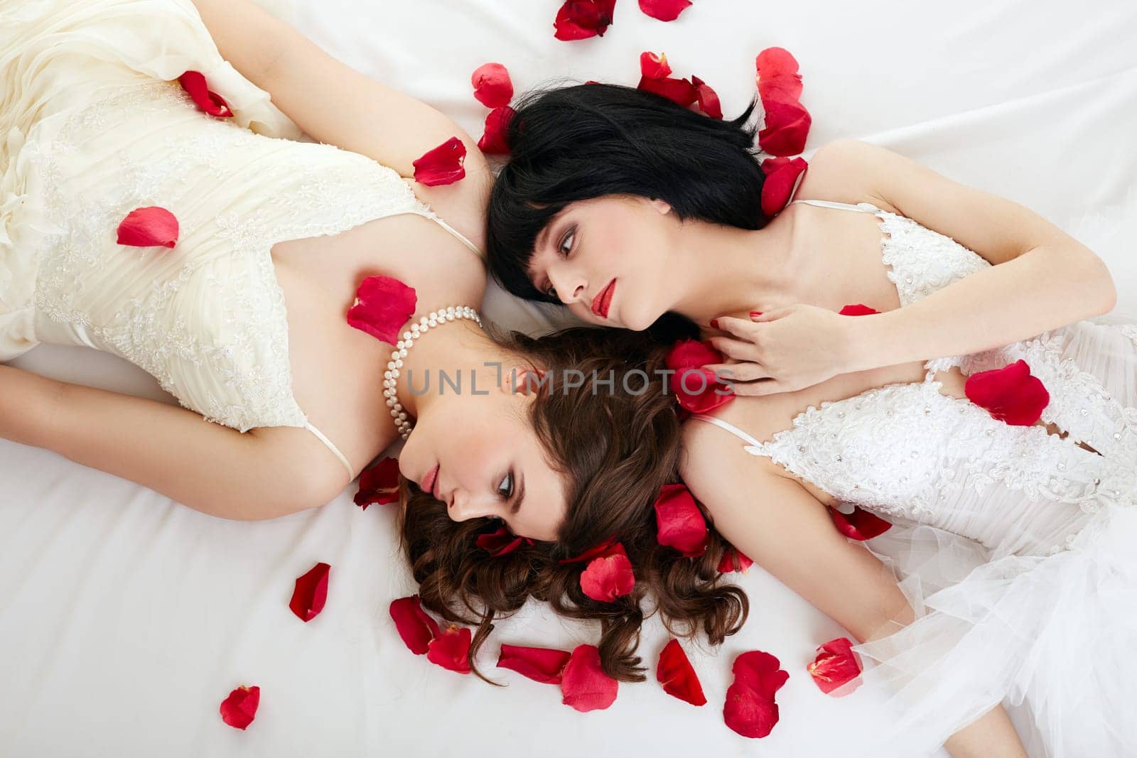 Concept of gay marriage. Lovely women posing in wedding dresses with petals