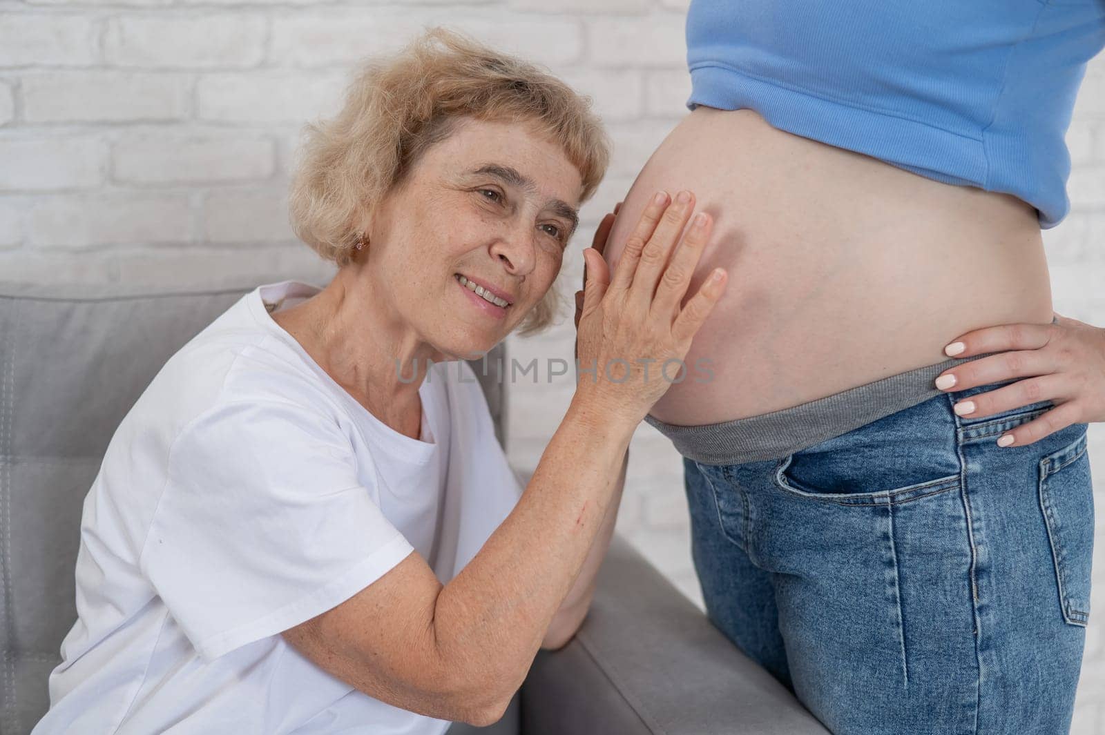 An elderly woman leans against the belly of her pregnant daughter. Close-up. by mrwed54