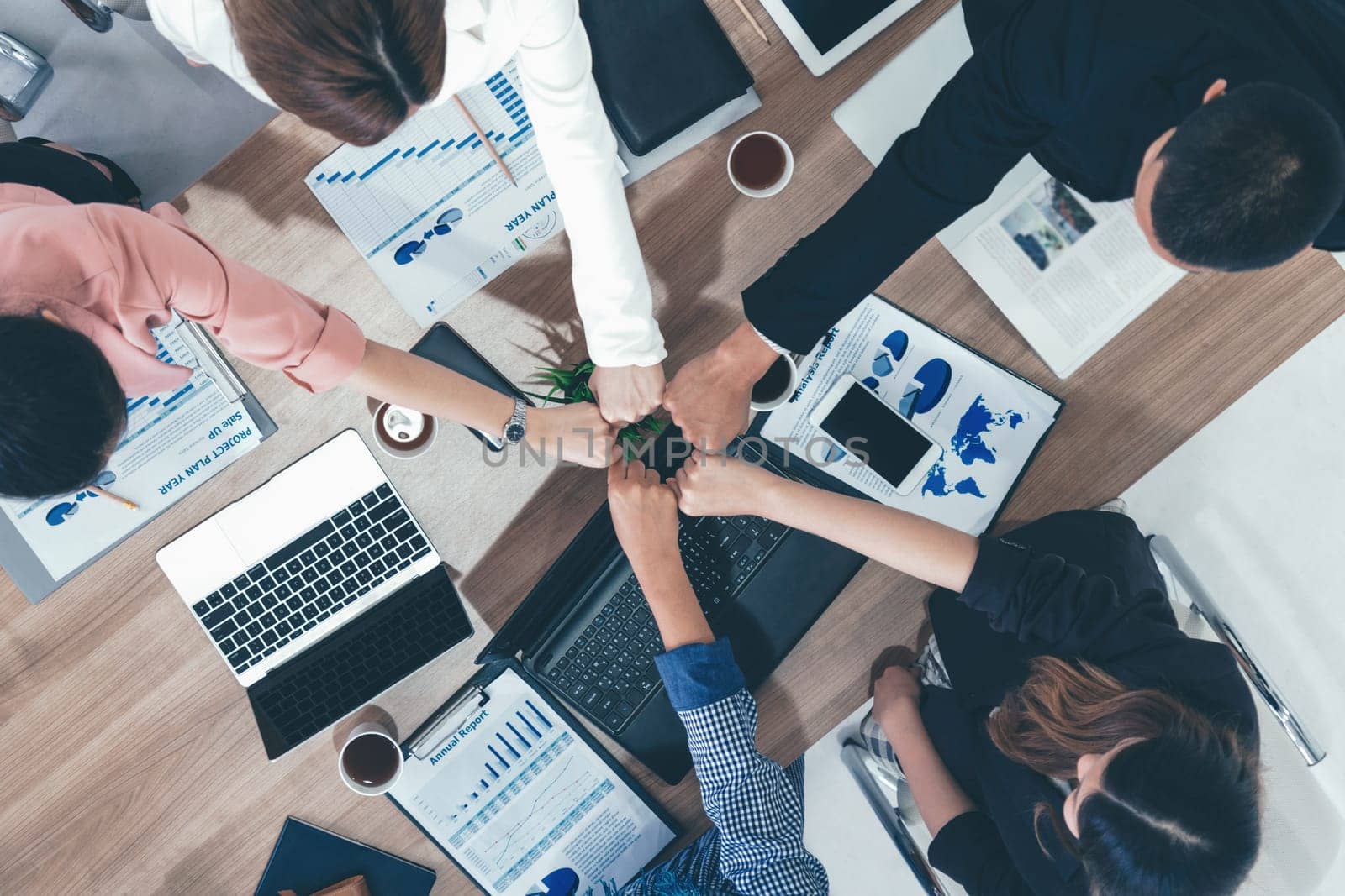 Businessmen and businesswomen joining hands in group meeting at multicultural office room showing teamwork, support and unity in business. Diversity workplace and corporate people working concept. uds