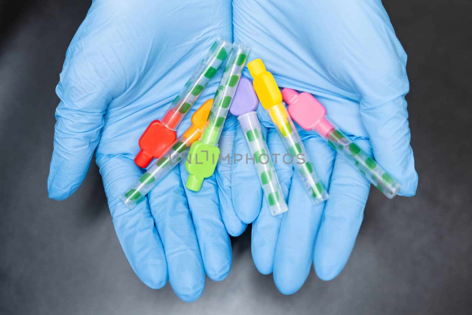 Close up Interdental Toothbrushes in dentists hands in rubber gloves on black background by vladimka