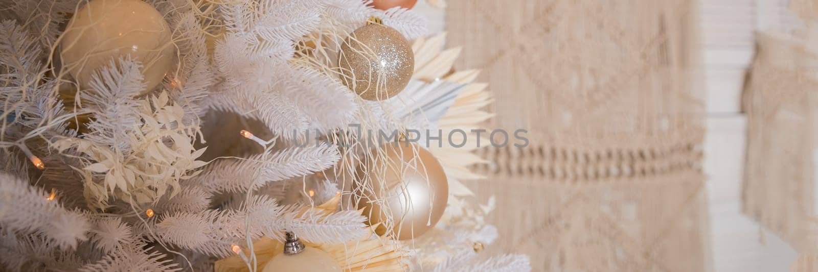 Close up of beautiful fir branches with shiny golden, silver and white baubles or balls, xmas ornaments and garland lights