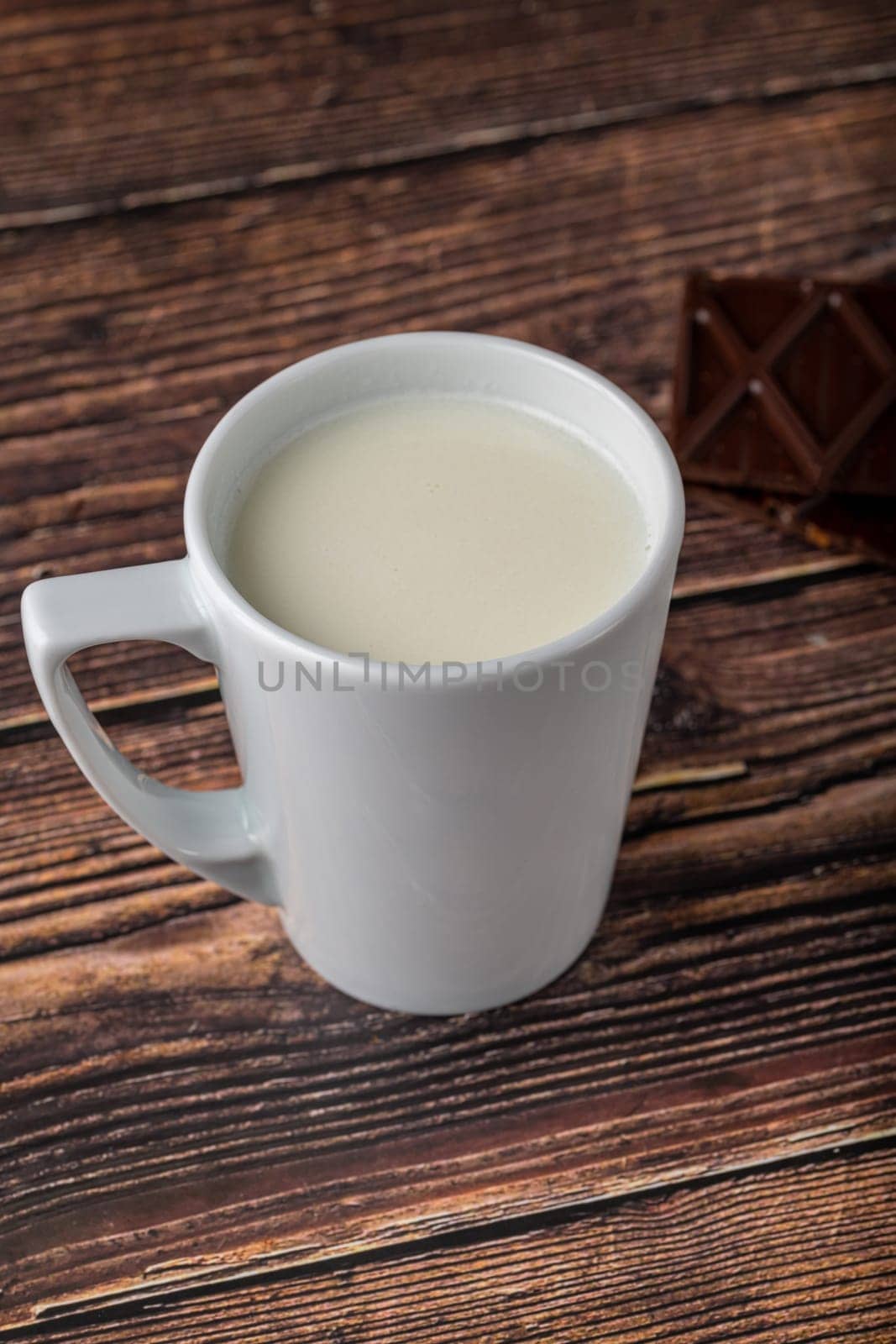 Milk with chocolate in black cup on wooden table by Sonat