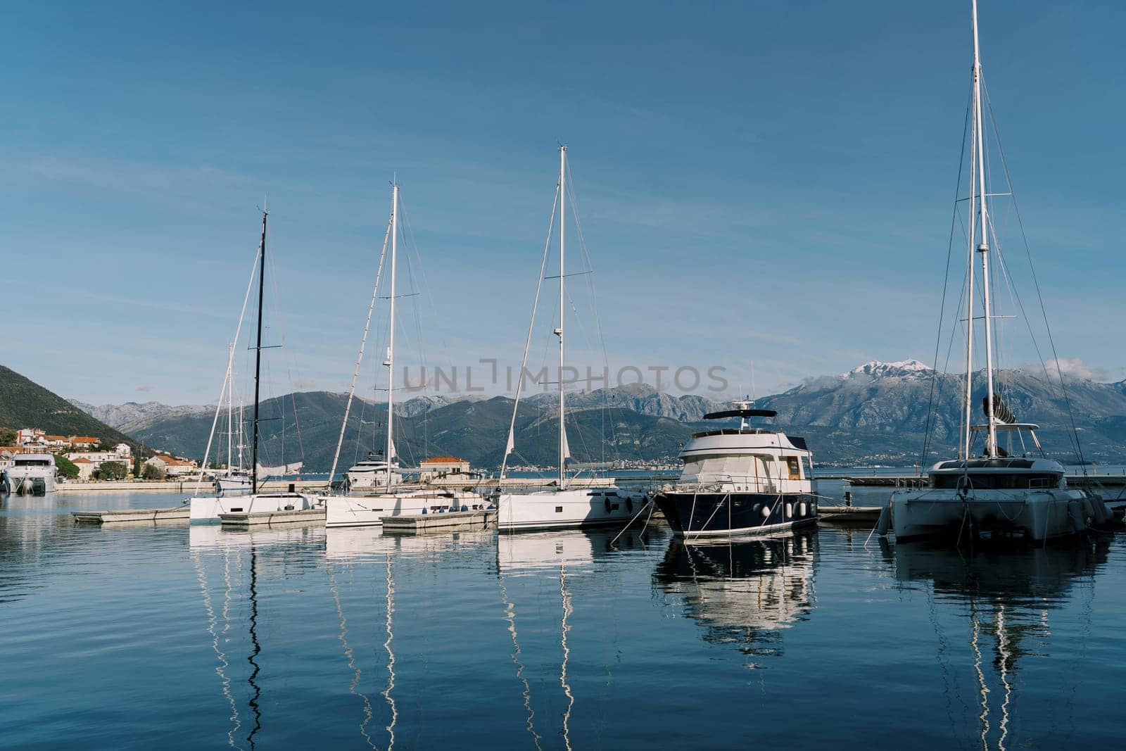 Row of sailing yachts stands at the pier against the backdrop of the mountains. High quality photo