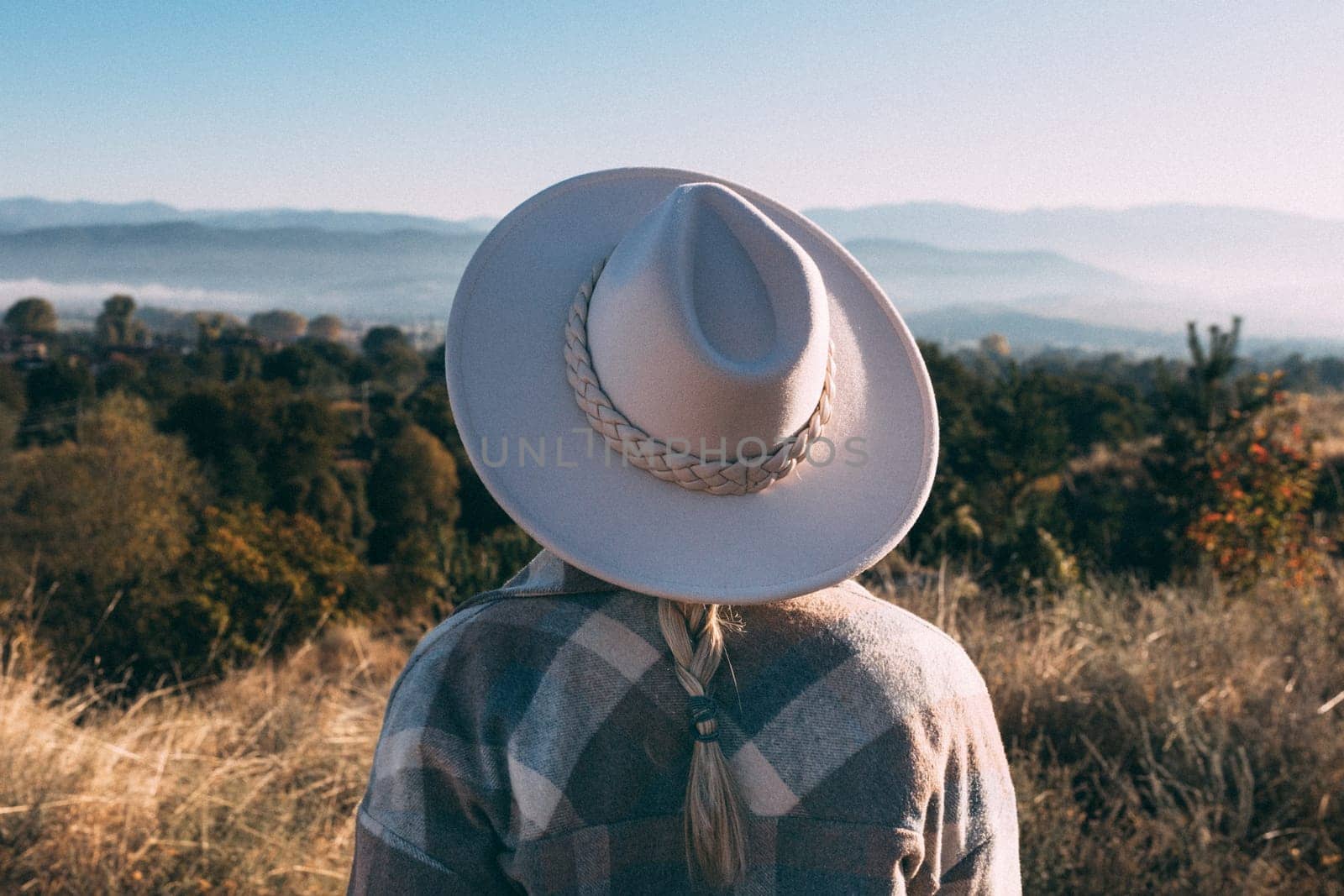 A woman stands in a meadow and looks at the mountains.