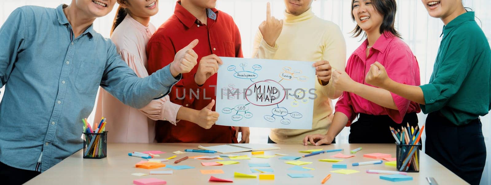 A cropped image of successful businesspeople presents new product marketing strategy using a mind map. Young creative business team brainstorm marketing idea together at modern office. Variegated.