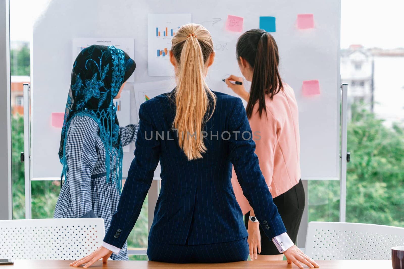 Multicultural working group. Team of businesswomen of different ethnicity, Caucasian, Asian and Arabic working together in team meeting at office. Multiethnic teamwork concept. uds