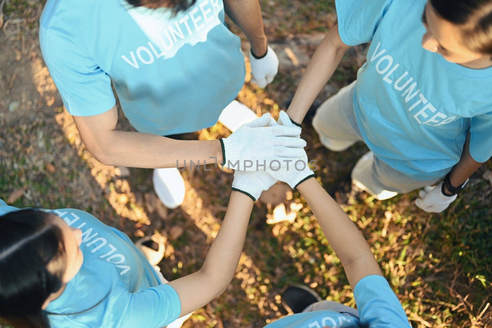Group of volunteers stacking their hands together showing the power of unity in charity work.