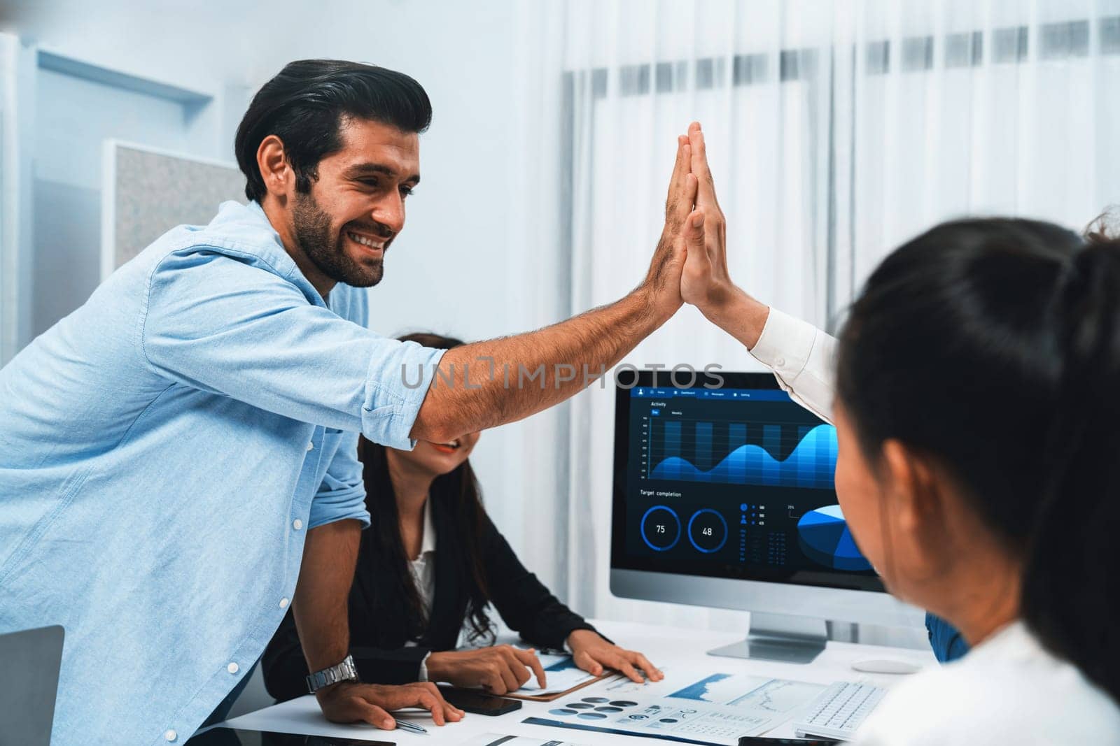 Analyst team leader celebrate and high five together with his colleague after successful data analysis meeting using FIntech software power with business intelligence or BI dashboard. Prudent