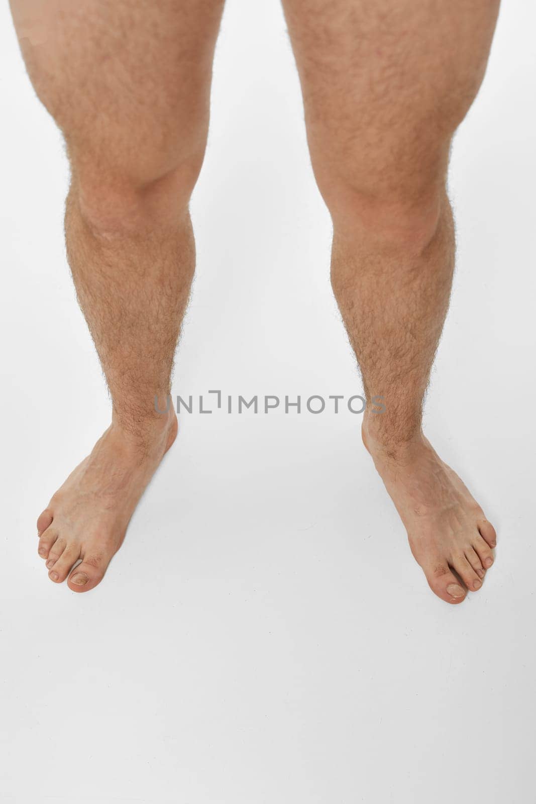 Barefoot male legs on white background. top view