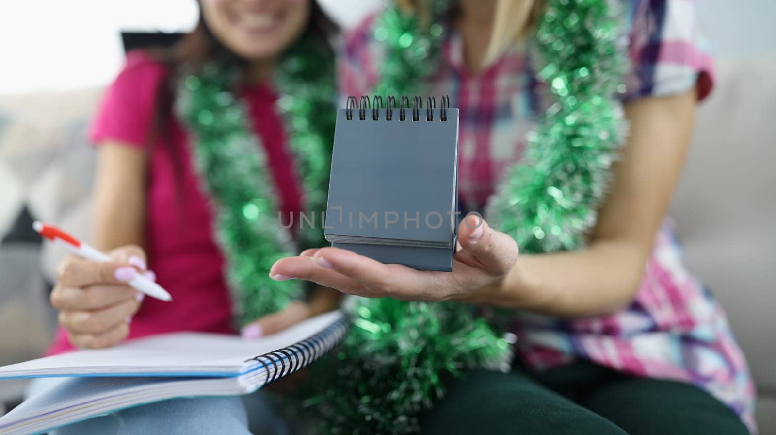Woman make plan for new year with pen in notebook. Girlfriend hold calendar in her hand.