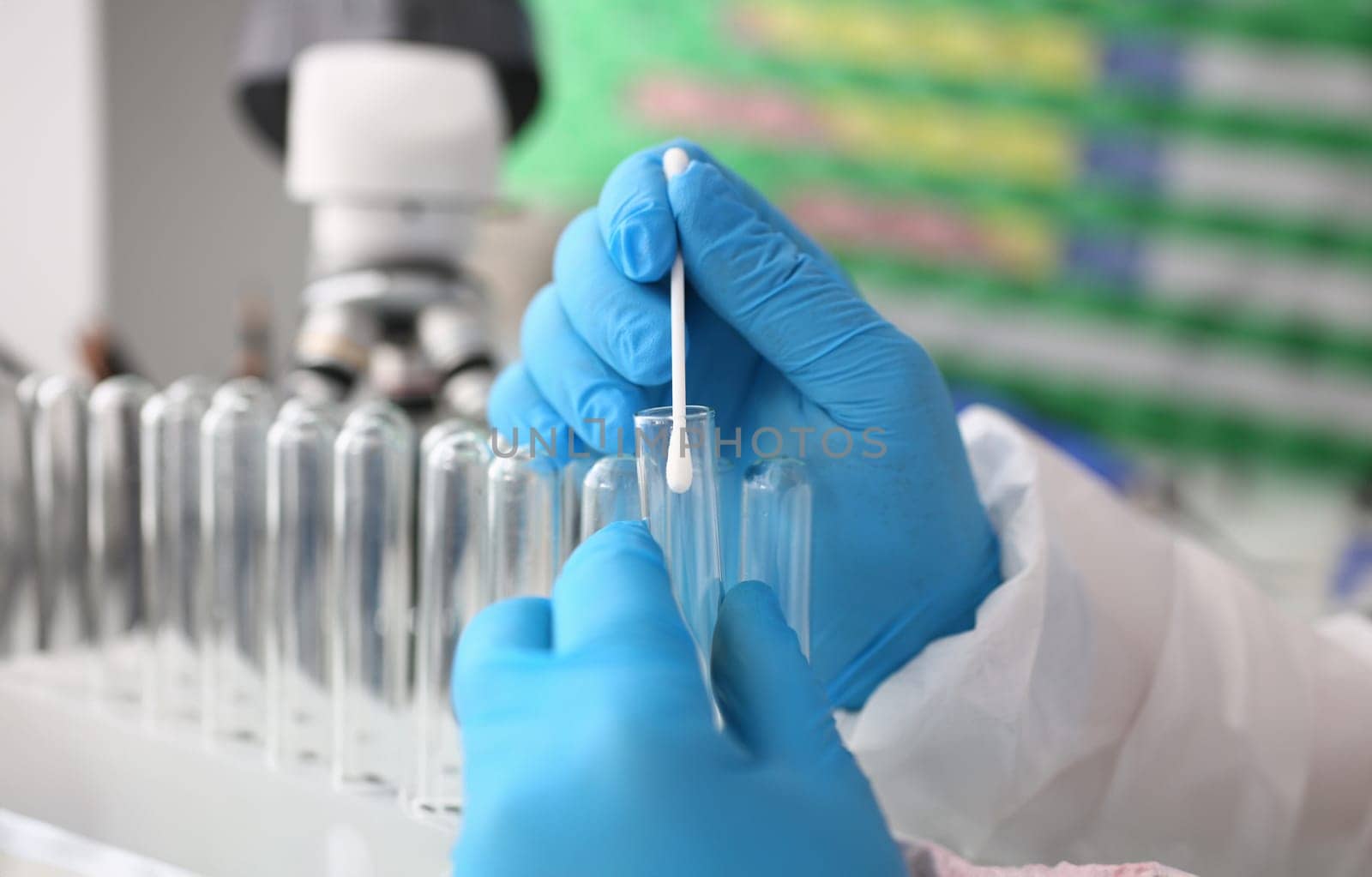 Forensic scientist conducting criminal investigation aganist laboratory background. Holds cotton swab with sample of dna and a test tube in his hand. Tets paternity concept.