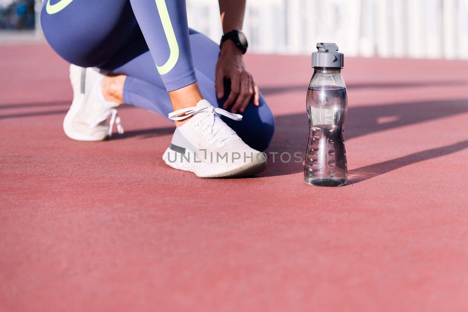 feet with running shoes of an unrecognizable female runner next to her water bottle, concept of healthy and active lifestyle, copy space for text