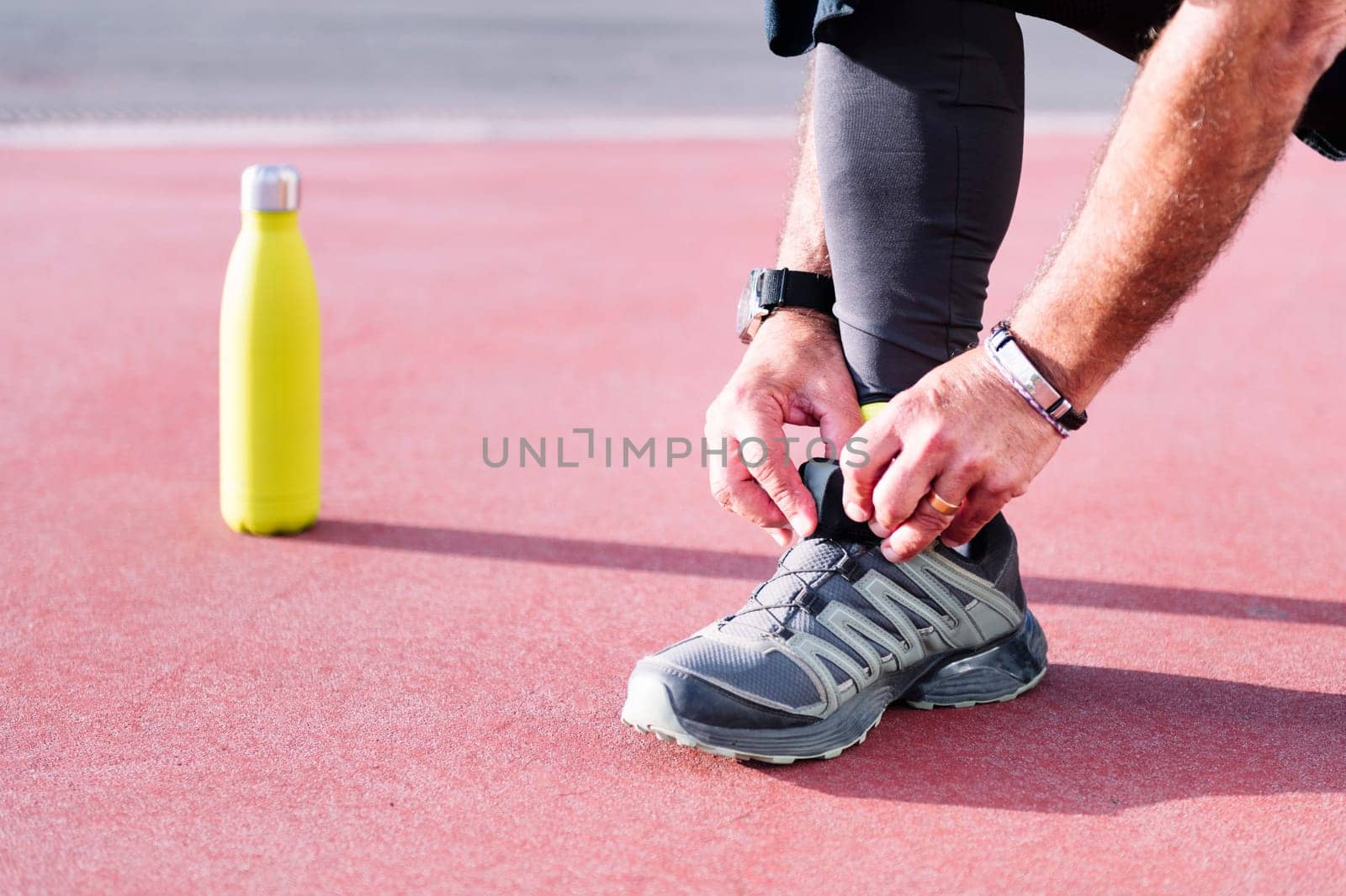 unrecognizable sports man tying running shoes before workout, concept of healthy and active lifestyle, copy space for text