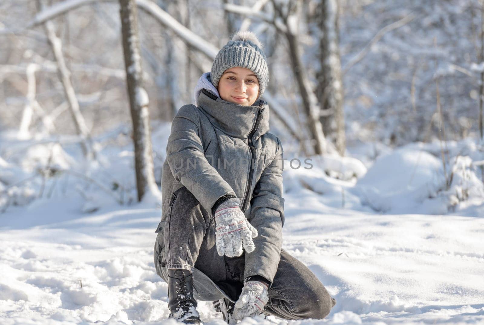 Teenage Girl Sits And Poses For A Photo In A Snow-Covered Forest In Winter